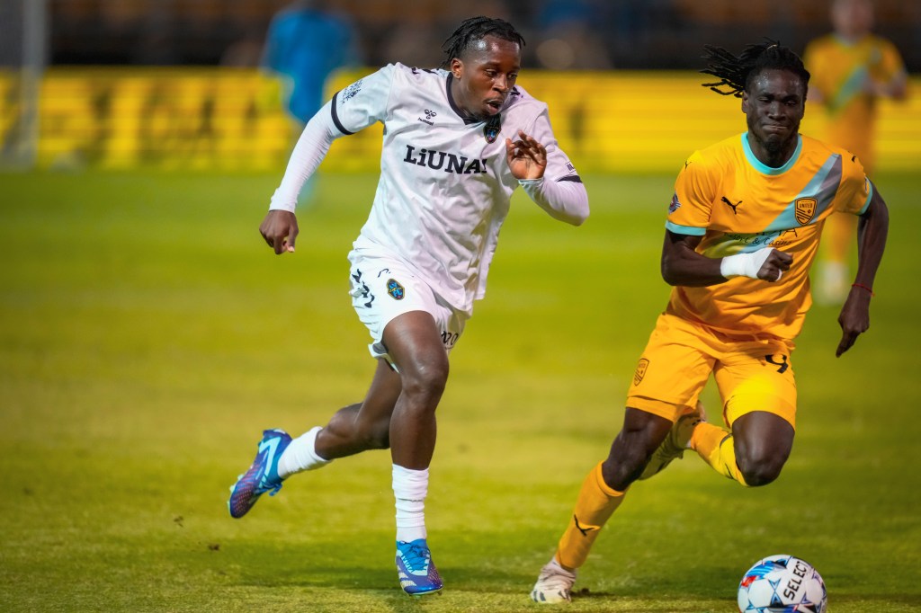 Las Vegas Lights midfielder JC Ngando racing against a New Mexico United player towards a soccer ball