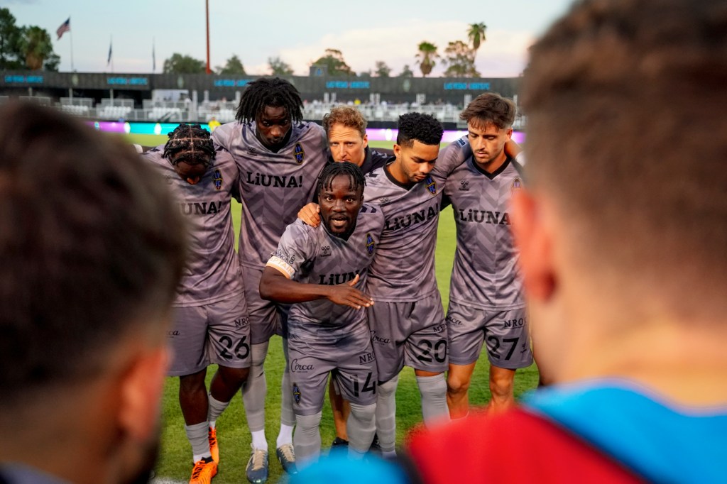 Las Vegas Lights FC players huddled around forward Soloman Asante for a team talk