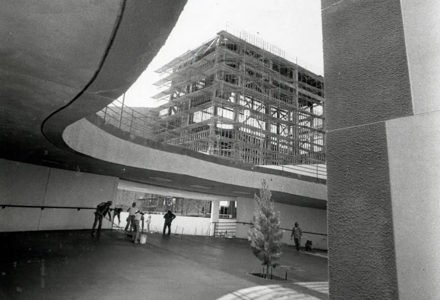 Construction workers finishing the concourse as the new stadium rises behind them
